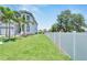 Landscaped front yard with lush grass, palm trees, and a white fence at 517 Treviso Dr, Apollo Beach, FL 33572