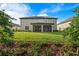 Spacious backyard featuring a well-maintained lawn, landscaping, and a covered patio at 33346 Kateland Dr, Wesley Chapel, FL 33545