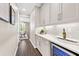 Butler's pantry with white cabinets, marble countertops, subway tile backsplash and built-in wine refrigerator at 33346 Kateland Dr, Wesley Chapel, FL 33545