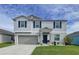Two-story house with gray siding, gray garage door, and landscaping at 17206 White Mangrove Dr, Wimauma, FL 33598