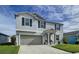 Two-story house with gray siding, gray garage door, and landscaping at 17206 White Mangrove Dr, Wimauma, FL 33598