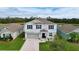 Two-story house with gray siding, gray garage door, and landscaping at 17206 White Mangrove Dr, Wimauma, FL 33598