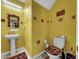 Small bathroom with pedestal sink, yellow walls, and egyptian decor at 17206 White Mangrove Dr, Wimauma, FL 33598