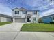 Two-story house with gray siding, gray garage door, and landscaping at 17206 White Mangrove Dr, Wimauma, FL 33598