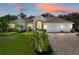 Beautiful single-story home with manicured lawn, mature landscaping, and a three-car garage at 13216 Legends Trl, Dade City, FL 33525