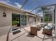 Covered lanai with sliding glass doors, featuring an outdoor seating area with wicker furniture, perfect for relaxing outdoors at 13216 Legends Trl, Dade City, FL 33525