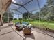 Screened lanai featuring an outdoor seating area with comfortable wicker furniture and a view of the landscaped backyard at 13216 Legends Trl, Dade City, FL 33525