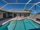A screened pool features a sun shelf and integrated steps, all surrounded by a brick patio at 13216 Legends Trl, Dade City, FL 33525
