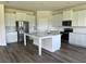 Modern kitchen with white cabinets, stainless steel appliances, large kitchen island, and durable floors at 908 160Th E Ln, Bradenton, FL 34212