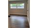 Cozy bedroom with dark floors, window, neutral walls, and an open door, offers a simple, relaxing space at 1920 N Highland Ave, Clearwater, FL 33755