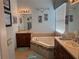 Bathroom featuring a soaking tub with tile surround, double sinks, and custom mirror and light fixtures at 15953 Cobble Mill Dr, Wimauma, FL 33598