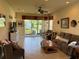 Living room with tile flooring, brown couches, a ceiling fan, and sliding doors to the backyard at 15953 Cobble Mill Dr, Wimauma, FL 33598
