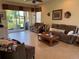 Living room with tile floors, brown couches, wooden coffee table, and sliding glass doors overlooking the pond at 15953 Cobble Mill Dr, Wimauma, FL 33598