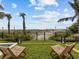A view of backyard with green grass and two chairs in the distance, set against a backdrop of palm trees and beach at 780 Eldorado Ave, Clearwater, FL 33767