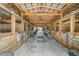 Interior view of a horse barn featuring wooden stalls, a metal roof, and ample space at 8602 State Road 674, Wimauma, FL 33598