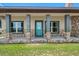 Charming front porch with stone accents, gray columns, and a bright blue door at 8602 State Road 674, Wimauma, FL 33598