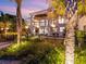 Beachfront home with palm trees and outdoor lighting at dusk at 780 Eldorado Ave, Clearwater, FL 33767