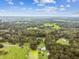 Wide aerial shot of a lush, green landscape with scattered homes, ponds, and dense trees under a partly cloudy blue sky at 3520 Leslie West Rd, Dover, FL 33527
