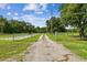 Long gravel driveway leading to a gated property surrounded by lush greenery and mature trees at 3520 Leslie West Rd, Dover, FL 33527