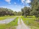 Long gravel driveway leading to the property through a green field, secured by a fence, offering privacy at 3520 Leslie West Rd, Dover, FL 33527