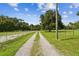 Long gravel driveway leading to a gated property surrounded by lush greenery and mature trees at 3520 Leslie West Rd, Dover, FL 33527