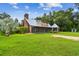 Exterior home view featuring a stone chimney, metal roof, and screened porch, with a lush lawn at 3520 Leslie West Rd, Dover, FL 33527
