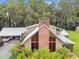 Striking home showcasing a stone chimney, walls of windows, an attached carport, and verdant tropical landscaping at 3520 Leslie West Rd, Dover, FL 33527
