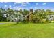 Expansive front yard featuring mature palms and lush green grass, framing the unique home design at 3520 Leslie West Rd, Dover, FL 33527