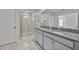 Bathroom features a double sink vanity, granite countertop, and large shower with glass door at 10066 Corso Milano Dr, Tampa, FL 33625
