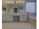 Bathroom featuring dual sinks, vanity seating area, a decorative glass block window, and modern lighting at 19334 Autumn Woods Ave, Tampa, FL 33647