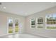 Spacious living room featuring white wood flooring, multiple windows, and glass doors to the backyard at 157 Hidden Estates Ct, Brandon, FL 33511