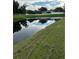 Serene pond view with lush green grass and a white fence in the background at 3464 Silverstone Ct, Plant City, FL 33566