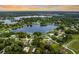 Scenic aerial shot of residential area featuring lakefront homes surrounded by mature trees and green lawns at 3744 E Lake Dr, Land O Lakes, FL 34639