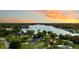 Picturesque aerial view of a lake at sunset, surrounded by lush greenery and waterfront homes at 3744 E Lake Dr, Land O Lakes, FL 34639