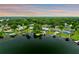 Aerial view of lakefront properties and lush greenery in a peaceful neighborhood at sunset at 3744 E Lake Dr, Land O Lakes, FL 34639