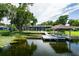 Lakeside view featuring a boat dock, screened lanai, and lush landscaping at 3744 E Lake Dr, Land O Lakes, FL 34639