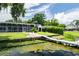 Backyard view showcasing a screened lanai, white rocking chairs, and a dock leading to the water at 3744 E Lake Dr, Land O Lakes, FL 34639