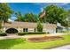 Charming single-story home featuring a well-manicured lawn, mature trees, and an American flag at 3744 E Lake Dr, Land O Lakes, FL 34639