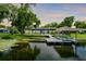 Waterfront home featuring a screened-in patio, a boat dock with a boat and a lush green lawn at 3744 E Lake Dr, Land O Lakes, FL 34639