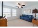 Bright bedroom with two windows, a blue sofa and ceiling fan at 17231 Holly Well Ave, Wimauma, FL 33598