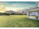 Large backyard with a covered patio area and a white fence during sunset at 7134 Heather Sound Loop, Wesley Chapel, FL 33545