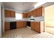 Well-lit kitchen with wood cabinets, black appliances, and a retro black and white tile floor at 10223 Us Highway 301, Dade City, FL 33525