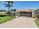 Single-Gathering home with two-car garage, palm trees, and well-maintained lawn at 10735 Collar Dr, San Antonio, FL 33576