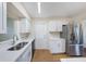 Kitchen with stainless steel refrigerator, white cabinets and counters, and wood flooring at 10735 64Th N Ave, Seminole, FL 33772
