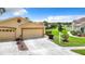 Tan two-car garage home with a landscaped yard and driveway at 13400 Norman Cir, Hudson, FL 34669