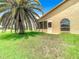Back exterior view of home with palm tree and grassy area at 13400 Norman Cir, Hudson, FL 34669
