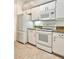 White kitchen appliances and cabinets with speckled granite countertops, including range, microwave and refrigerator at 761 Tremont Greens Ln # 61, Sun City Center, FL 33573