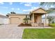 Tan house with a landscaped yard, paved driveway, and porch at 2707 W Leroy St, Tampa, FL 33607