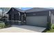 Beautifully designed home with a gray garage door, dark gray exterior, stone accents, and lovely landscaping at 3001 E 25Th Ave, Tampa, FL 33605