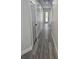 Bright hallway with gray wood floors, white walls, and a decorative front door at the end at 3001 E 25Th Ave, Tampa, FL 33605